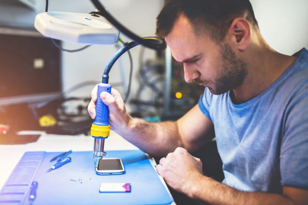 expert man repairing smartphone at workplace